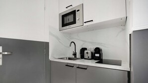A compact kitchen with a built-in microwave, a toaster, and a sink. - Cosy Studio for 2P With A/C - Near Montmartre (Paris)