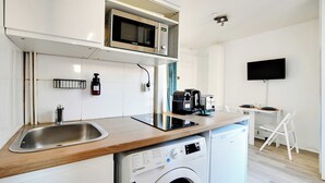 A compact kitchen with a built-in washing machine, a microwave, and a coffee maker. - Cosy Studio - 2P - Place de la Bastille (Paris)