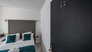 Ein Hotelzimmer mit einem großen Bett, einem Nachttisch, einer Nachttruhe und einer Tür mit der Nummer 32.
