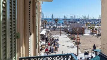 Un balcón con vistas a un puerto deportivo, zona de estar exterior y cielo despejado.
