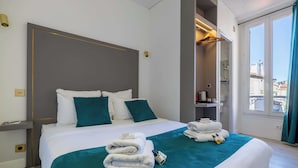 Camera d'albergo con un letto grande, un comodino, uno specchio e vista sulla città attraverso una finestra.