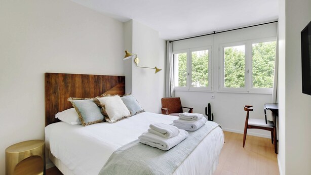 Ein modernes Schlafzimmer mit einem großen Bett, einem Holzkopfende, einem Schreibtisch und einem Stuhl.