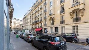A street view with parked cars, buildings with balconies, and a clear sky. - Cosy Studio - 4P - Palais des Congres (Paris)