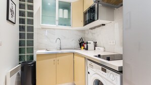 A compact kitchen with a built-in washer and dryer, a microwave, and a window with frosted glass. - Cosy Studio - 4P - Palais des Congres (Paris)