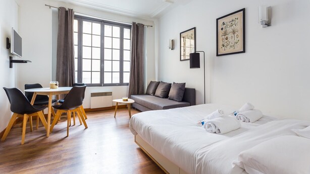 A hotel room with a bed, a sofa, a dining table with chairs, a TV, and artwork on the walls. - Cosy Studio - 4P - Palais des Congres (Paris)