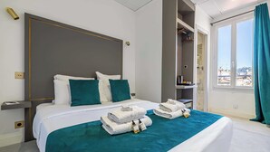 A hotel room with a large bed, a wardrobe, and a window with curtains. - Hotel Avaton - Cosy Bedroom - Cannes Centre (Cannes)