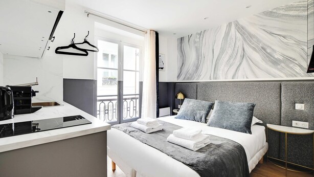 A modern hotel room with a bed, bedside table, and a large window.