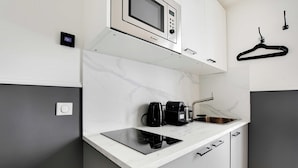 A compact kitchen with a built-in microwave, a coffee maker, and a sink.