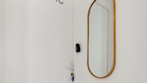 A white door with a number plate, a gold-framed mirror, and a small marble-topped table.