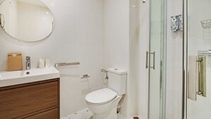 Un bagno moderno con un water bianco, cabina doccia in vetro e mobile lavabo in legno con specchio.
