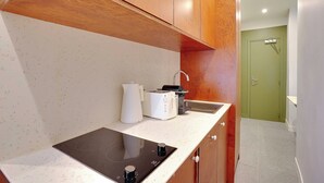 A modern kitchen with wooden cabinets, a built-in induction cooktop, a coffee maker, and a toaster. - Elegant Studio - 2P - Republique (Paris)