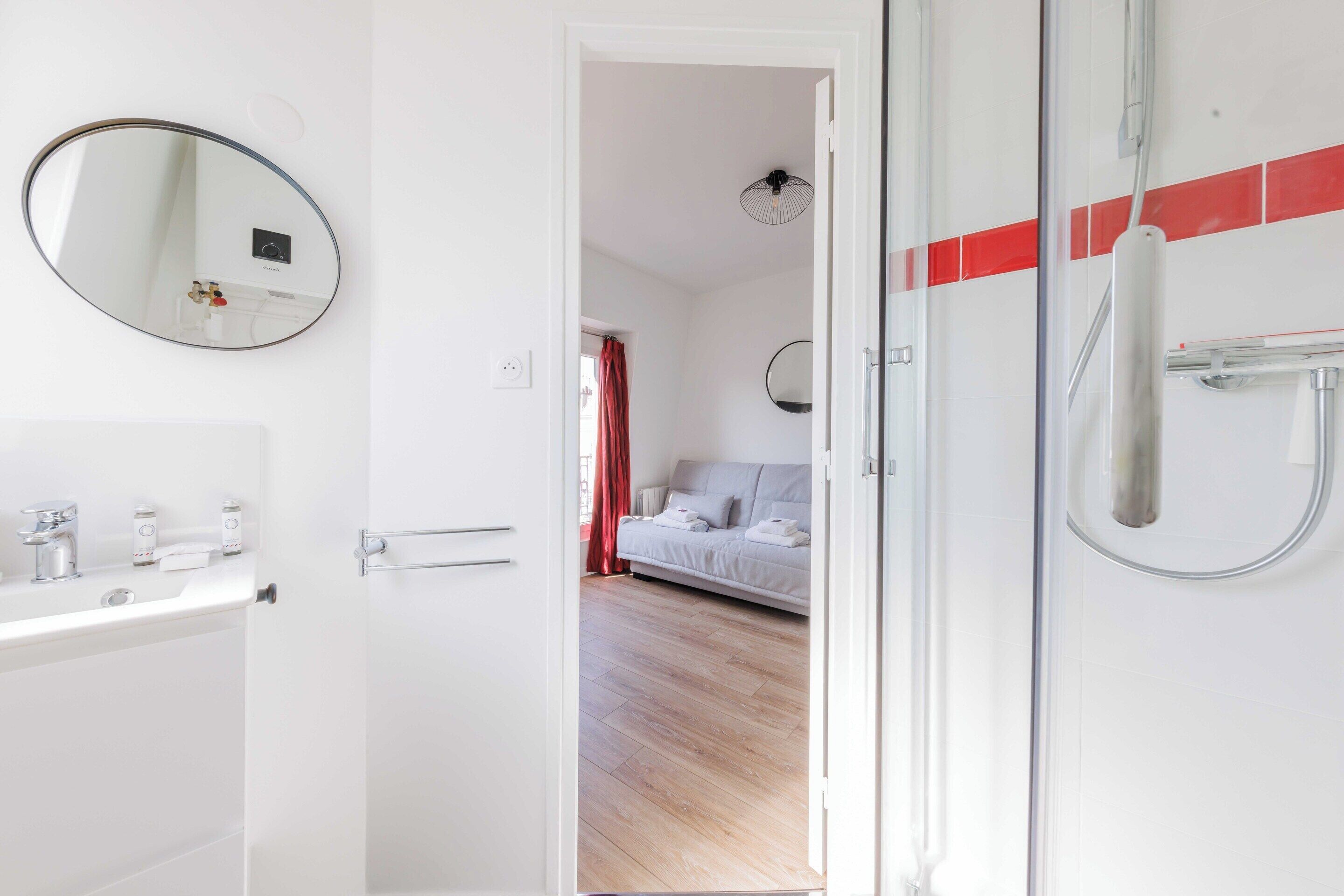 Een moderne badkamer met een wit wastafelmeubel, spiegel en douche.
