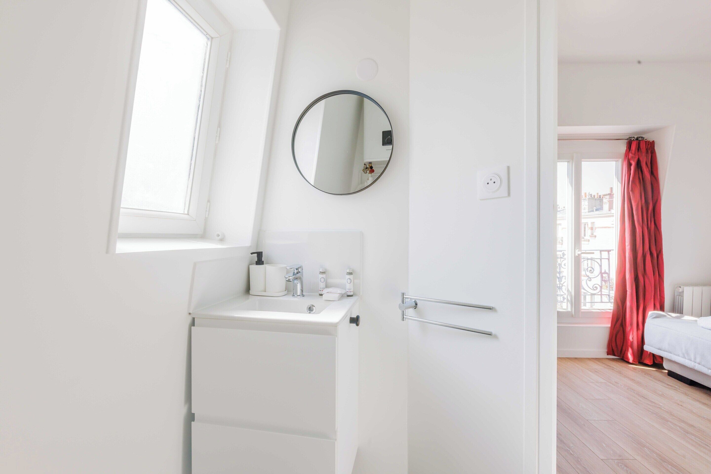 A modern bathroom with a white sink, mirror, and towel rack.
