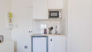 Une cuisine compacte équipée d’un four à micro-ondes, d’un petit réfrigérateur et d’un évier.