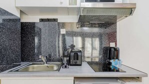 Uma cozinha moderna com uma pia de aço inoxidável, uma torradeira e uma cafeteira no balcão.