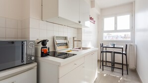 A modern kitchen with a microwave, coffee machine, and a sign on the counter. - Superbe Studio - 4P - Trocadero (Paris)
