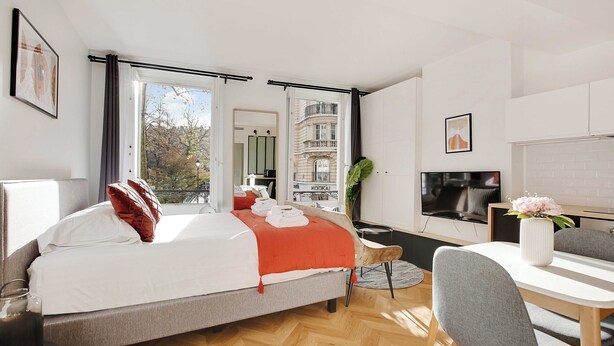 A modern hotel room with a bed, a dining table, and a TV. - Welcoming Studio for 2 People - Bastille (Paris)