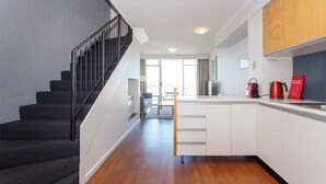 A modern apartment with a staircase, a kitchen with white cabinets, and a view to the outside. - This apartment is a 2 bedroom(s), 2 bathrooms, located in Fremantle, WA. (Fremantle)