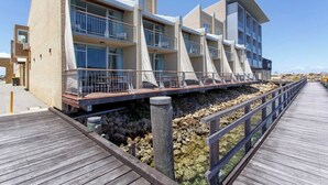 A modern hotel with multiple balconies, a wooden deck, and a rocky shoreline. - This apartment is a 2 bedroom(s), 2 bathrooms, located in Fremantle, WA. (Fremantle)