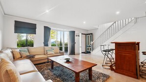 Ein geräumiges Wohnzimmer mit einer Couch, einem Couchtisch und einer Treppe zu einer weiteren Ebene.