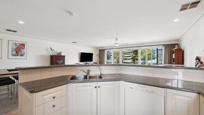Eine moderne Küche mit einer gebogenen Kücheninsel, eingebauten Geräten und einem großen Fenster mit Blick ins Freie.