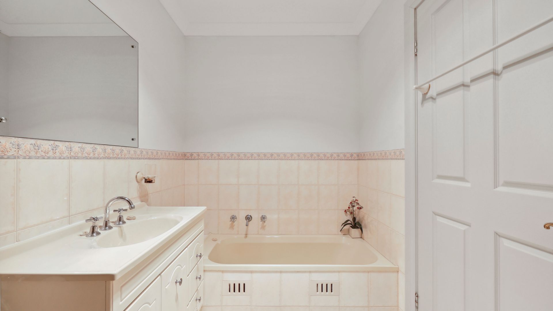 A bathroom with a double sink vanity, a bathtub, and a mirror above the vanity.