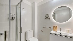 Un bagno moderno con box doccia in vetro, un water bianco, un mobile lavabo con specchio e un portasciugamani.