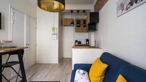 A compact living space with a kitchenette, a dining area, and a sofa with yellow cushions. - Cosy and Peaceful Studio - 2P - Nation/voltaire (Paris)