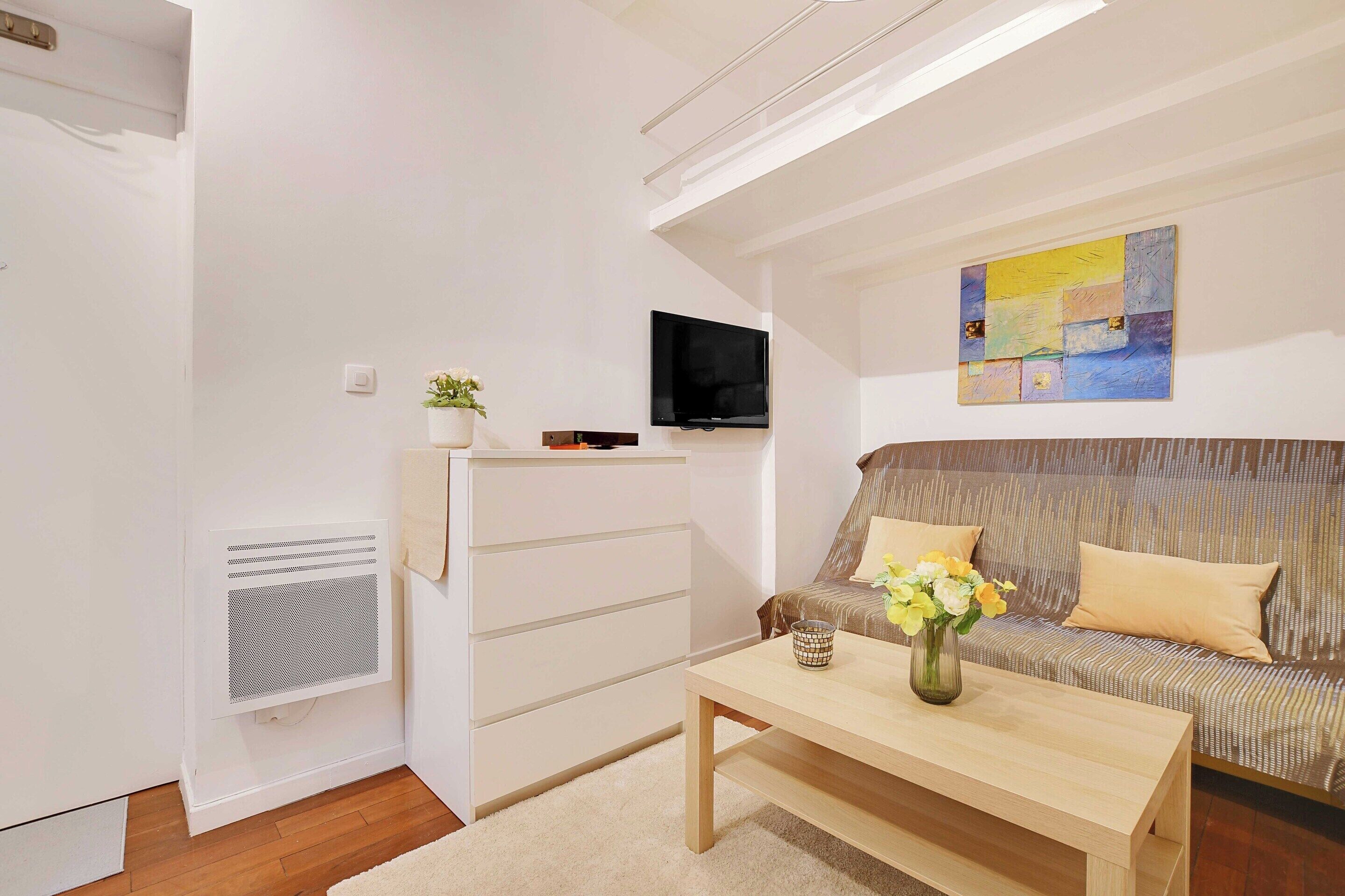 Una sala de estar moderna con un sofá, una mesa de centro, un televisor y un cuadro en la pared.