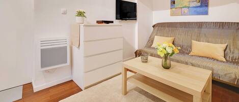 A modern living room with a sofa, a coffee table, a TV, and a painting on the wall.