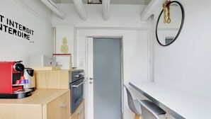 Una cucina compatta con una macchina da caffè, un piccolo forno e un'anta che dà su un'altra stanza.
