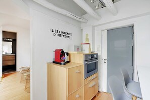 Une cuisine compacte équipée d’un four encastré, d’une machine à café et d’un petit réfrigérateur.