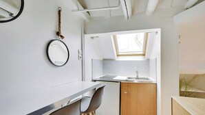 Una cucina compatta con un lavello, un piccolo oblò e uno specchio a parete.