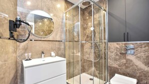 Un baño moderno con ducha de vidrio, tocador blanco y un inodoro.