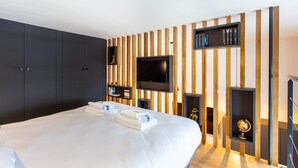 Ett hotellrum med en stor säng, en platt-TV, träpanel på väggen och en hylla med böcker och en jordglob.