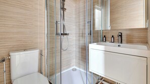 A modern bathroom with a glass shower enclosure, a white toilet, and a vanity with a mirror. - Cosy Studio for 2 People - Malakoff (Malakoff)
