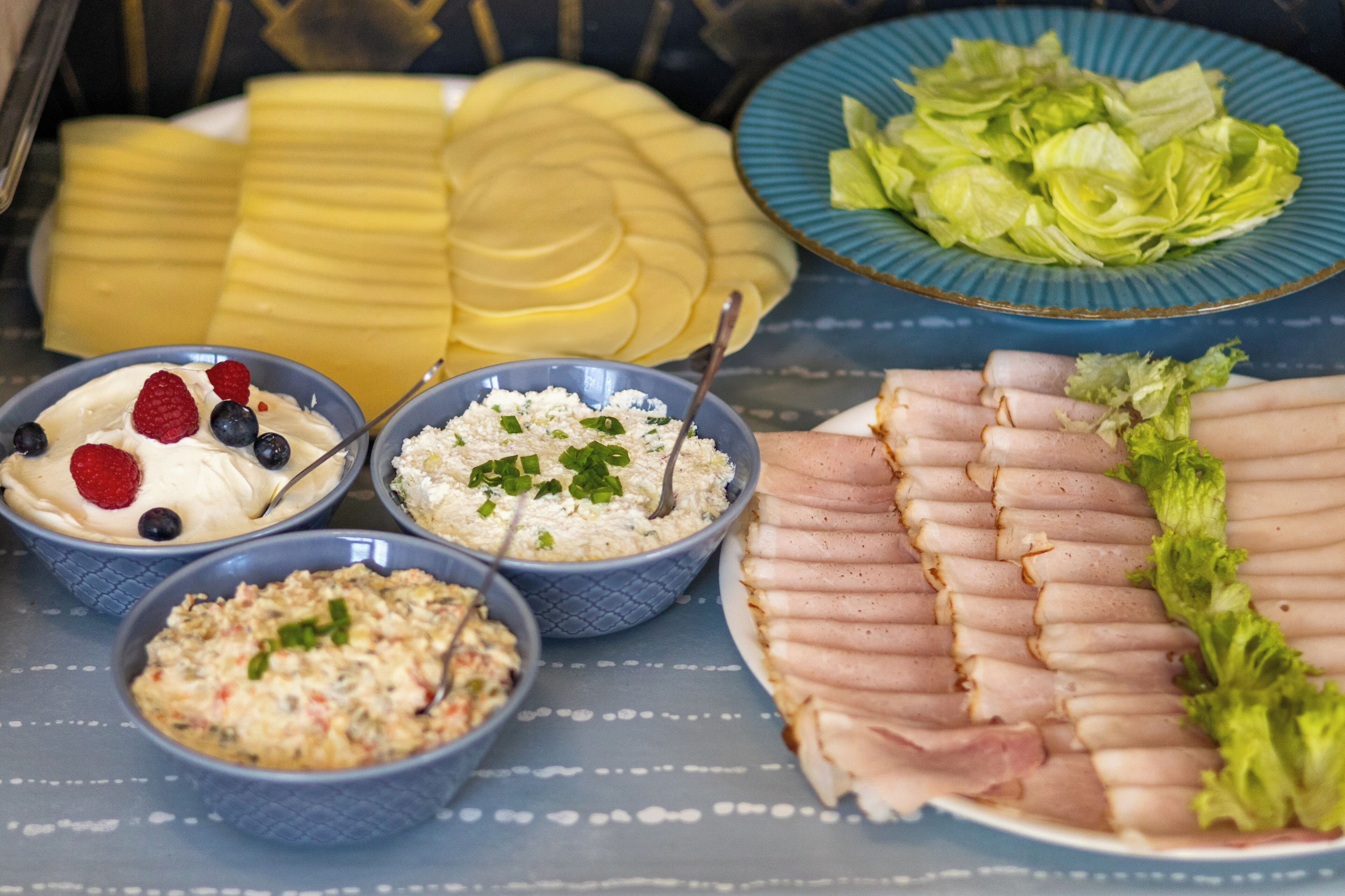 A buffet table with various food items including sliced meats, fruits, and salads.
