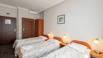 Una habitación de hotel con tres camas, cabeceros de madera y lámparas de noche.