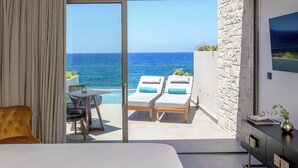 Una habitación moderna con un gran ventanal corredero que da a un balcón con dos tumbonas y una mesa.