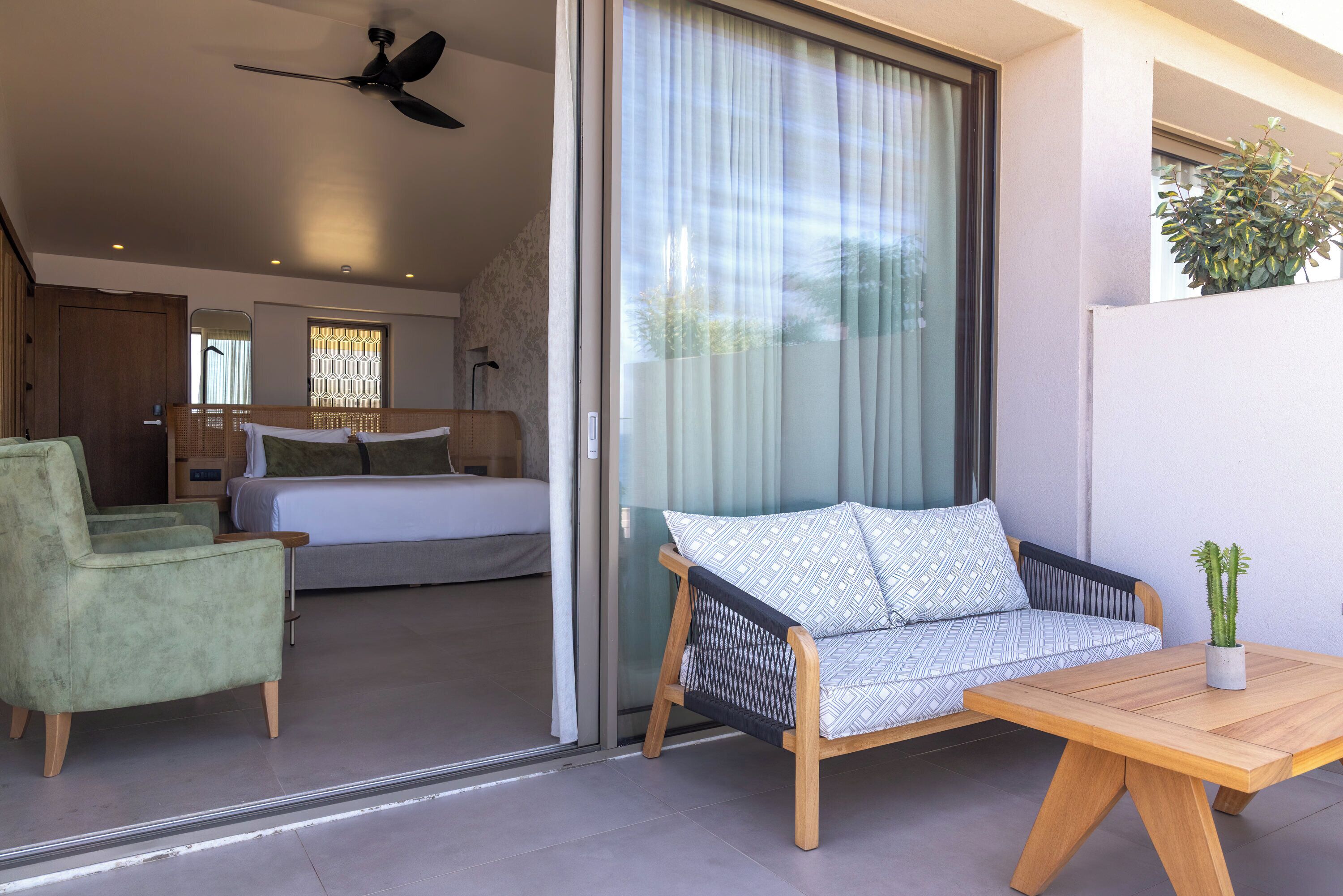 Una habitación moderna con una cama, un sofá, una mesa de madera y un ventilador de techo.