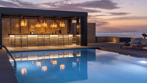 Un área de piscina moderna con bar y sillones de descanso con vistas al mar.