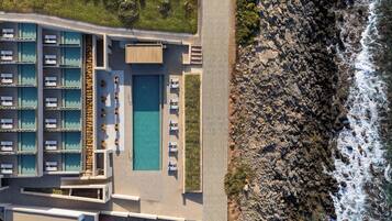 An aerial view of a hotel with multiple swimming pools, a beachside location, and rocky coastline.