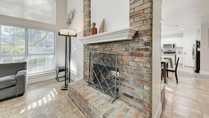 A living room with a fireplace, a sofa, and a dining area with a table and chairs. - 2 Story Home in Round Rock Sleeps 16 Guests (Round Rock)