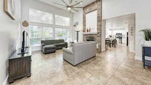A spacious living room with a gray sofa, a ceiling fan, and a fireplace. - 2 Story Home in Round Rock Sleeps 16 Guests (Round Rock)