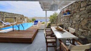 Ein Poolbereich mit Holzterrasse, Liegestühlen und einem Tisch mit Stühlen.
