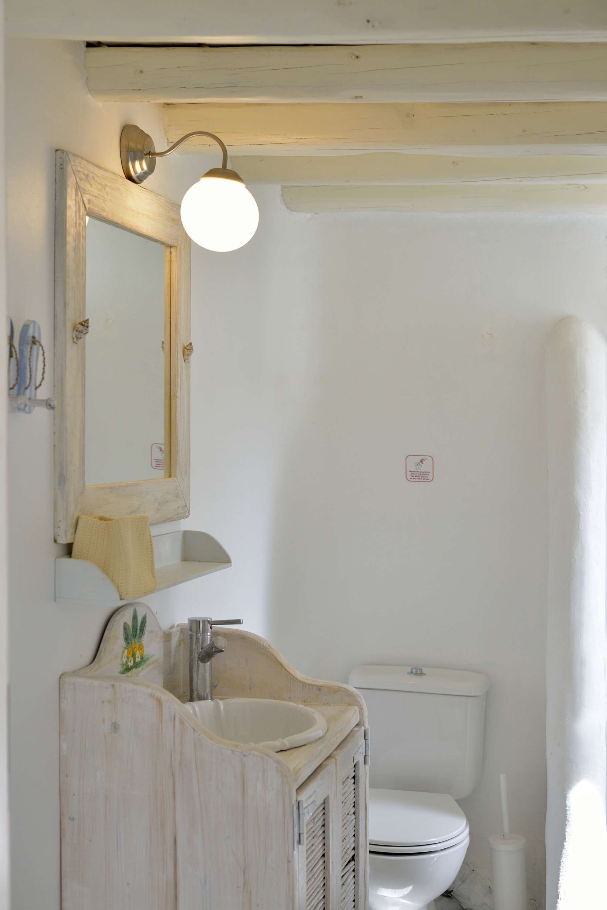 Een badkamer met een wit wastafel, een spiegel, een lamp en een toilet.