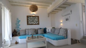Ein Wohnzimmer mit weißem Sofa, einem Glastisch und einer Wanddekoration.