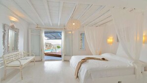 Ein Schlafzimmer mit einem großen Bett, einer Bank und Blick auf ein Freibad.