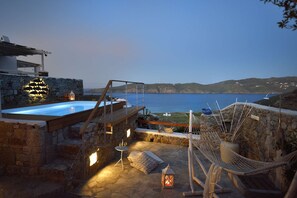 Une terrasse sur le toit avec une piscine, des murs en pierre et un hamac.