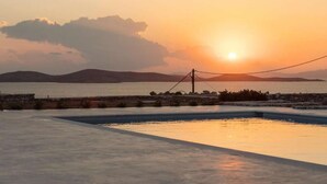 A swimming pool with a sunset view, a stone wall, and a power line. - Villa Conza 5 bed in Mykonos (Mykonos)